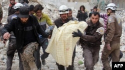 FILE - Members of the Syrian civil defense, known as the White Helmets, remove a victim from the rubble of a destroyed building following a reported airstrike in the northwestern city of Idlib, March 15, 2017.