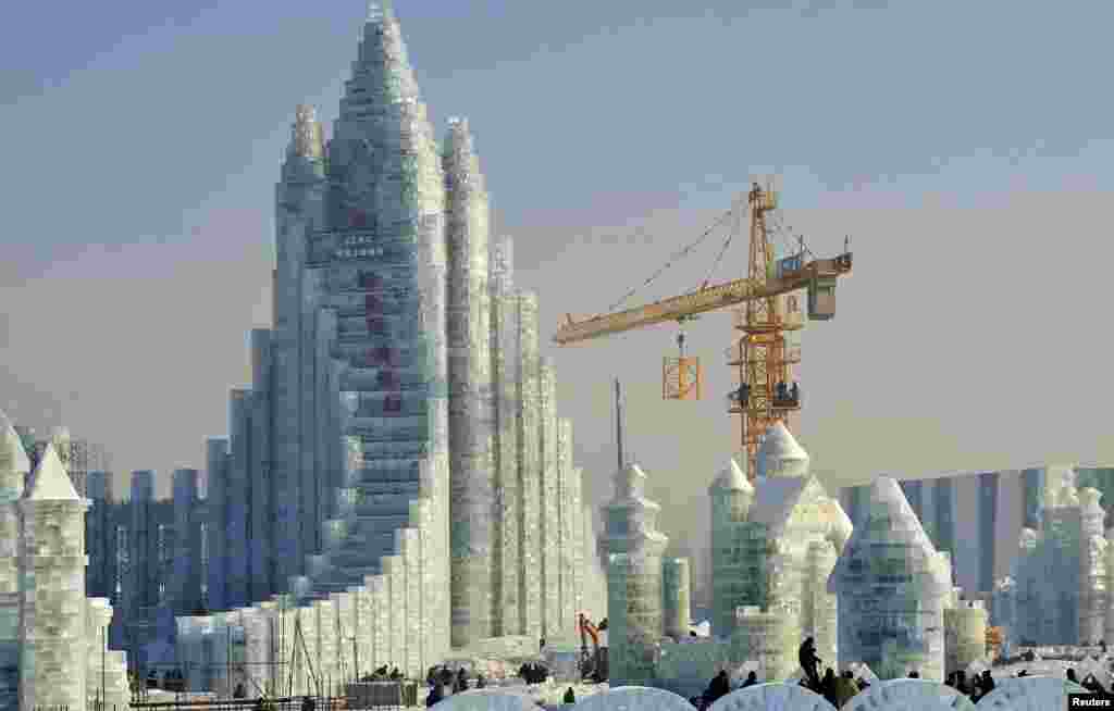 哈尔滨国际冰雪节的冰雕城堡，有工人和起重机在施工（2013年12月27日）