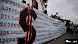 FILE - Demonstrators hold a banner made from three thousand two-bolivar-bills, that is equivalent approximately to $1 according to the black market exchange rate, in Caracas, Venezuela, June 10, 2017.