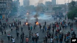 Anti-government protesters set fires and block roads while security forces fire tear gas during a protest in Baghdad, Iraq, Oct. 2, 2019. 
