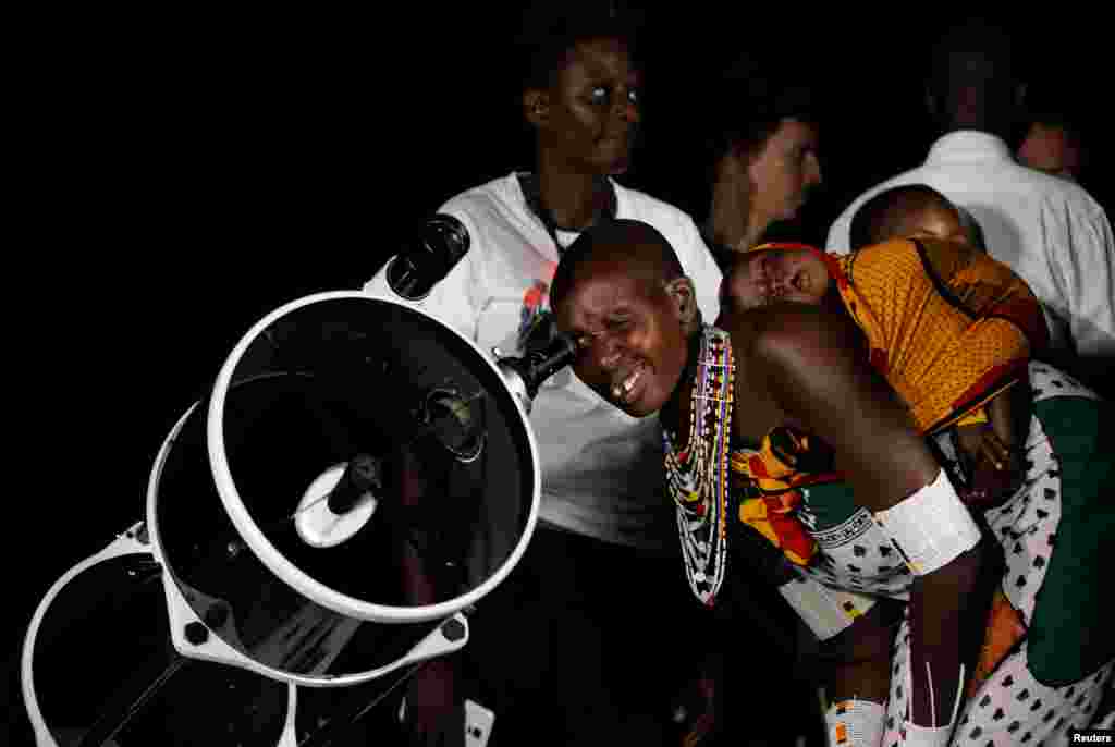 Seorang perempuan suku Maasai menggunakan teleskop untuk menyaksikan "supermoon" di desa Oloika, Shompole, dekat perbatasan Kenya-Tanzania.