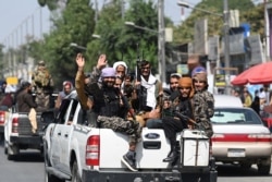 Taliban fighters wave as they patrol in a convoy along a street in Kabul on Sept. 2, 2021.