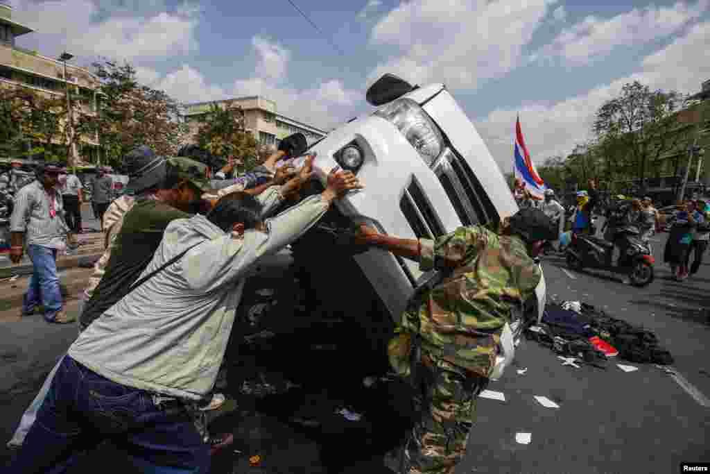 Anti-government protesters lift a police car after clashes with Thai riot police officers, near Government House, Bangkok Feb. 18, 2014. 
