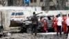Seorang petugas polisi berjaga-jaga saat pekerja Bulan Sabit Merah mengeluarkan jenazah korban di lokasi ledakan bom mobil bunuh diri di dekat kediaman presiden, di Mogadishu, Somalia, 25 September 2021. (Foto: Reuters)