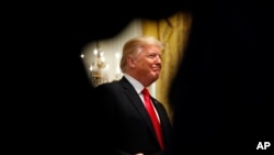 FILE - President Donald Trump smiles as he is applauded while speaking about taxes, June 29, 2018, during an event in the East Room of the White House in Washington. 