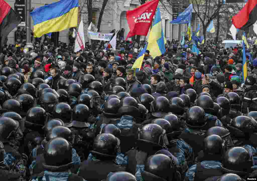 Police stand guard over protesters in front of parliament during a demonstration in support of EU integration, Dec. 3, 2013.