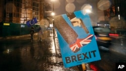 Vehicles drive past an anti-Brexit placard that is placed near the Parliament in London, Jan. 29, 2019. 