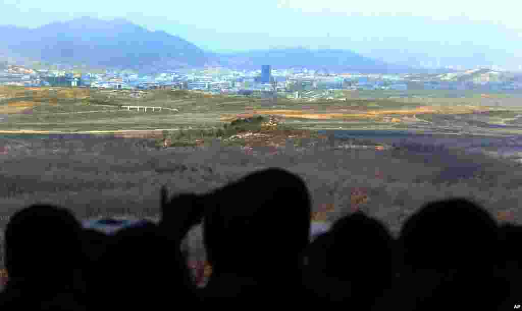 Visitors look at the industrial complex in Kaesong, North Korea, through binoculars at Dora Observation Post in the demilitarized zone (DMZ) near the border village of Panmunjom, in Paju, South Korea, April 9, 2013.