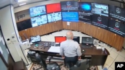 In this undated frame grab taken from video shared with The Associated Press by a self-identified hacker group called "The Justice of Ali," a guard looks at surveillance screens taken over by the group, at Evin prison in Tehran, Iran. 