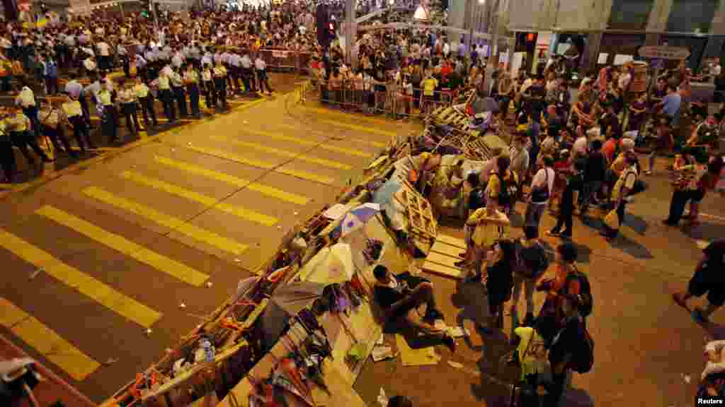 Policemen stand by a barricade as pro-democracy protesters continue blocking an area at the Mongkok shopping district of Hong Kong, Oct. 19, 2014.