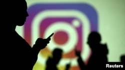 Siluet para pengguna ponsel di depan layar yang menampilkan logo Instagram, 28 Maret 2018. (Foto:Ilustrasi).