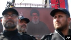 Hezbollah security forces stand guard as their leader Sheik Hassan Nasrallah speaks via a video link on a screen in the southern suburb of Beirut, Lebanon, Sept. 10, 2019.