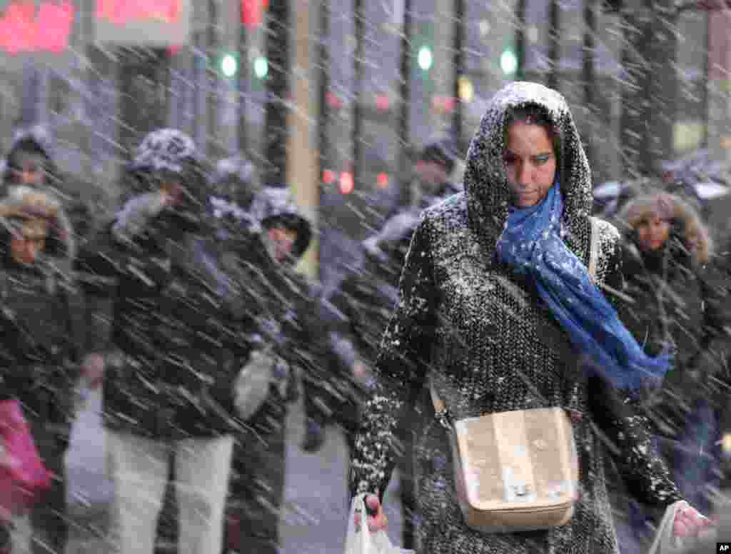Para pejalan kaki melewati hujan salju di New York (26/1). (AP/Seth Wenig)