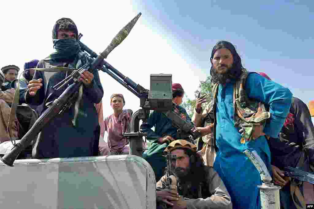Taliban fighters sit over a vehicle on a street in Laghman province, Afghanistan, Aug. 15, 2021.