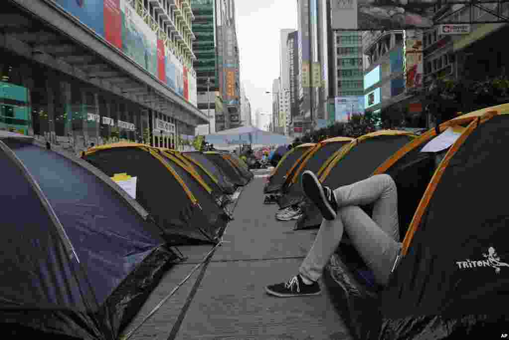 Seorang demonstran beristirahat di tenda dekat jalan utama di distrik Mongkok, Hong Kong (15/10). (AP/Vincent Yu)
