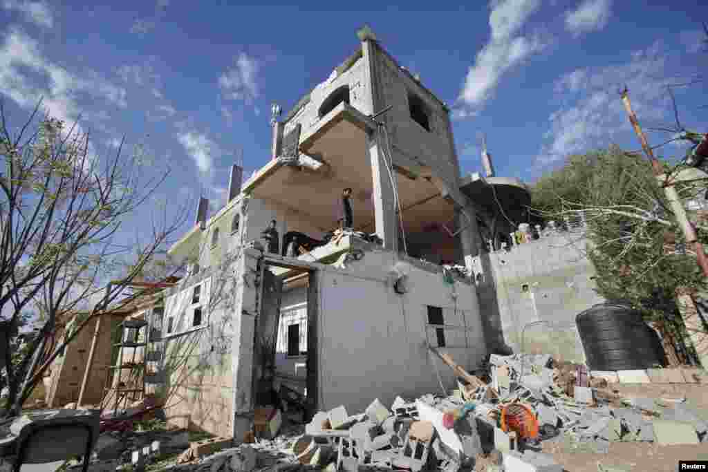 Palestinians inspect a house that witnesses said was damaged in an Israeli strike, in the central Gaza Strip, Dec. 25, 2013.