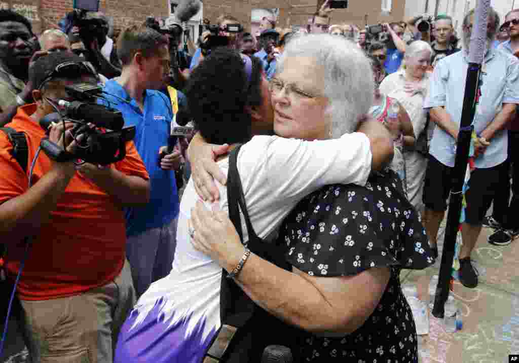 Susan Bro, mother of Heather Heyer who was killed during last year's Unite the Right rally, embraces supporters after laying flowers at the spot her daughter was killed in Charlottesville, Va., Sunday, Aug. 12, 2018.