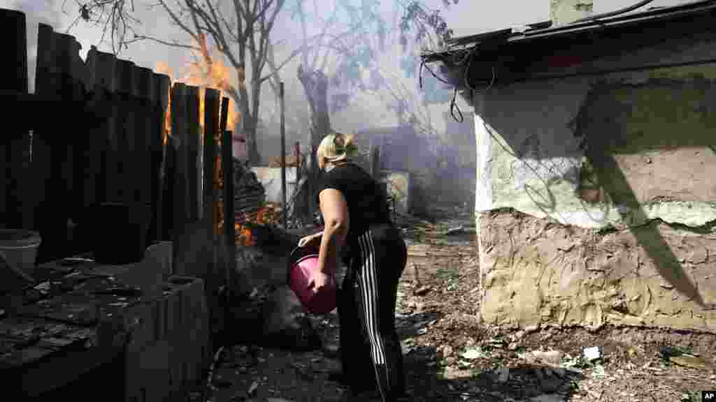 A local woman puts out the fire at her burning house after shelling in Donetsk, eastern Ukraine, Sept. 7, 2014.