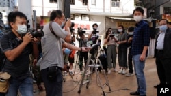 香港立法会前议员许智峰（右二）在交保获释走出警察局后被记者围住。（2020年11月18日）