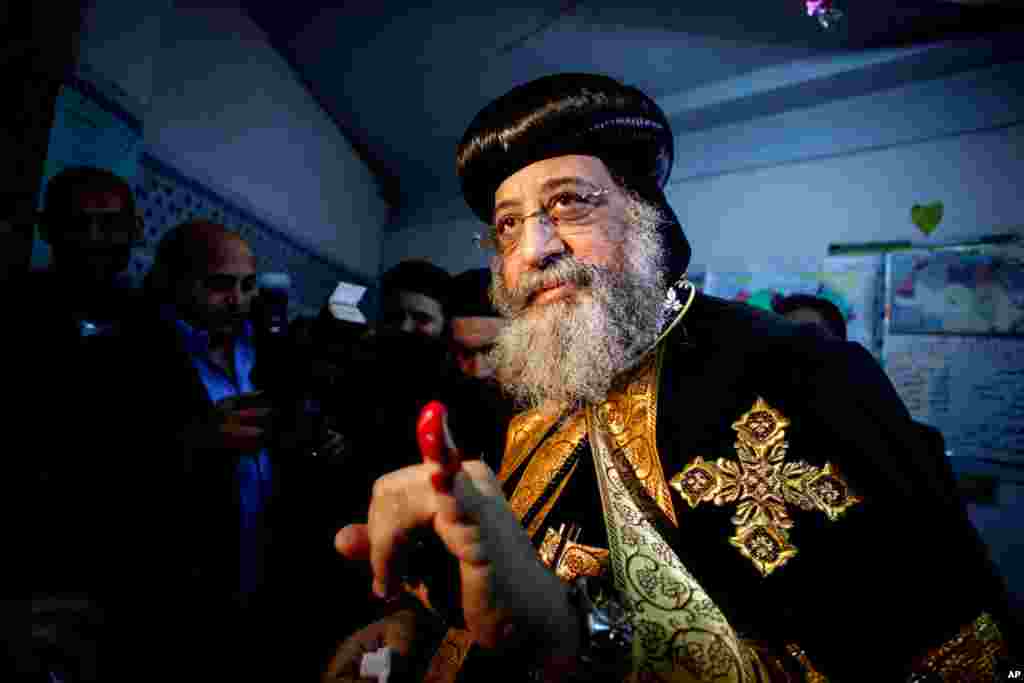 Coptic Pope Tawadros II shows his ink-stained finger after voting in the country's constitutional referendum at a polling station in Cairo, Jan. 14, 2014.