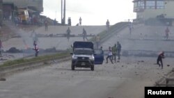 Protesters throw stones at a riot police vehicle on a main road in Sonfonia District in Conakry, Guinea, Oct. 14, 2019, in this still image taken from video. 