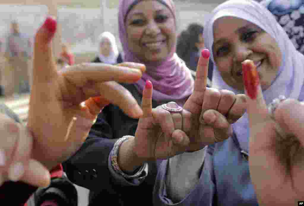 Women show their inked fingers after casting their votes at a polling station in Cairo. Egyptians are voting on a draft for their country's new constitution.