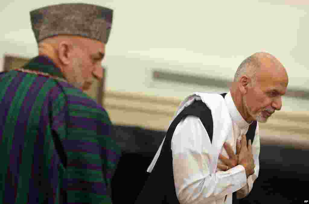 Ashraf Ghani Ahmadzai leaves after signing a power-sharing deal as president Hamid Karzai, left, stands at the presidential palace in Kabul, Afghanistan, Sept. 21, 2014.