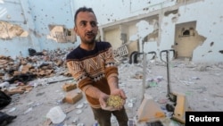 Seorang penduduk Palestina memegang bahan makanan mentah di tempat serangan Israel di gudang bantuan, yang terletak di kamp pengungsian Al-Nuseirat di Tengah Jalur Gaza, 14 Maret 2024. (Foto: REUTERS/Ahmed Zakot)
