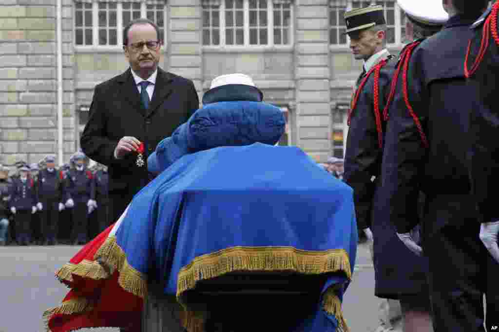 French President Francois Hollande holds a medal in front of the coffin of Police officer Clarissa Jean-Philippe during a ceremony to pay tribute to the three police officers killed in the attacks, in Paris, France, Jan. 13, 2015.