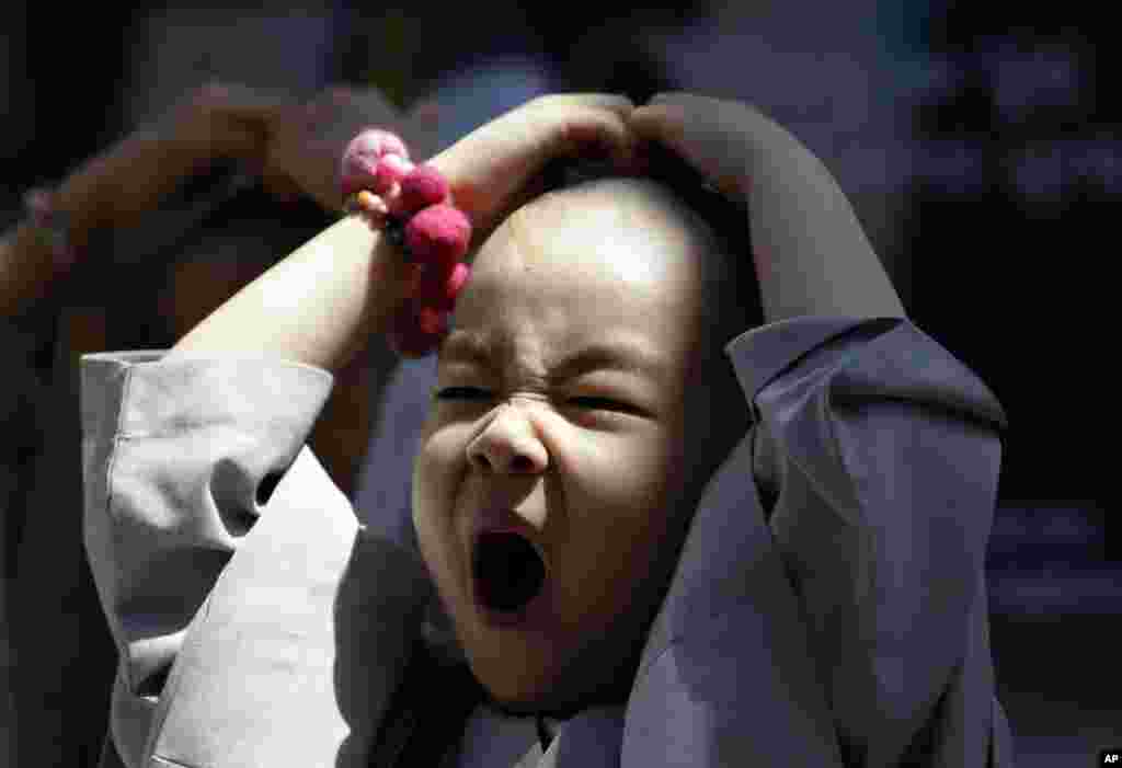 Seorang anak berkepala gundul, di antara sepuluh anak yang untuk mengikuti pengalaman hidup biksu selama tiga minggu yang disebut 'Perkemahan Budha Kecil', menguap di sebuah kuil di Seoul, Korea Selatan.
