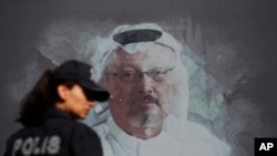 FILE - A Turkish police officer walks past a picture of slain Saudi journalist Jamal Khashoggi prior to a ceremony, near the Saudi Arabia consulate in Istanbul, marking the one-year anniversary of his death, Oct. 2, 2019.