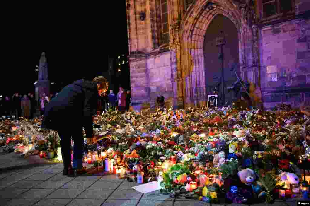 A woman places a tribute with flowers and candles left near the 'Alter Markt' Christmas market, where a man drove a car into the crowd through an emergency exit route on Dec. 20, in Magdeburg, Germany.