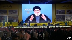 Hezbollah leader Sayyed Hassan Nasrallah delivers a broadcast speech through a giant screen, during a rally marking the12th anniversary of the 2006 Israel-Hezbollah war, in Beirut, Lebanon, Aug. 14, 2018.