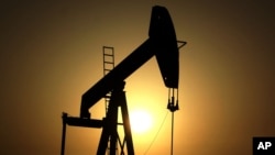 FILE - The sun sets behind an oil pump in the desert oil fields of Sakhir, Bahrain, June 8, 2011. OPEC nations have agreed in theory on the need to reduce their production to help boost global oil prices during a meeting last month in Algeria, but disagre