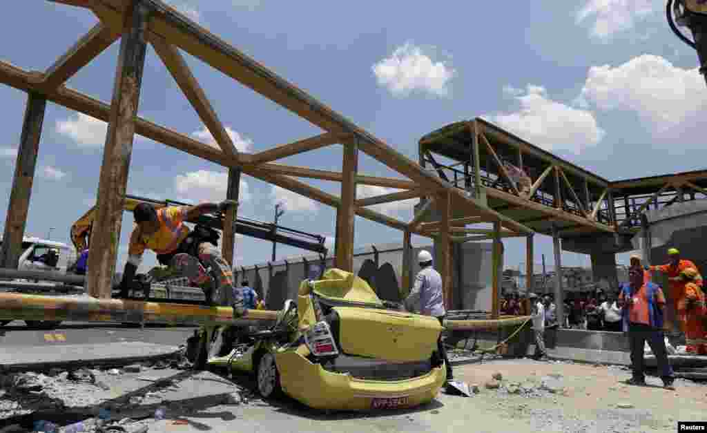 A worker jumps over a taxi crushed by a pedestrian bridge after a dump truck hit the bridge on the Linha Amarela expressway in Rio de Janeiro, Brazil. According to local media, the accident left at least five dead and four wounded.