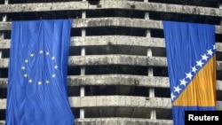 Workers place large European Union and Bosnian flags on a war damaged central government building in Sarajevo November 25, 2005. The Balkan country of four million people, known formally as Bosnia and Herzegovina, marks this month the 10th anniversary of