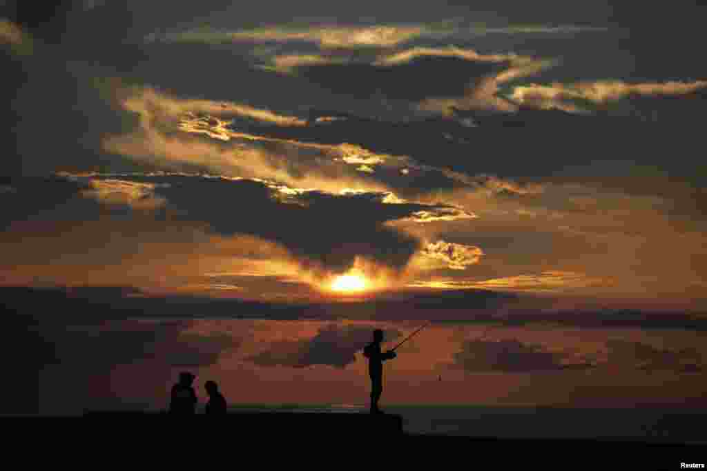 A fisherman holds his rod as the sun sets on Havana's seafront boulevard 'El Malecon', Cuba, Aug. 1, 2013.