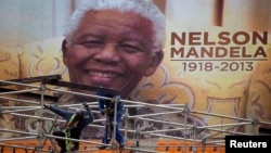 Foto Nelson Mandela di layar digital untuk upacara pemakaman di stadion First National Bank di Johannesburg, 9 Desember 2013.