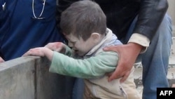 Syrians help an injured child following an alleged airstrike by government forces near a school in the northern Syrian city of Aleppo, Jan. 21, 2014. 