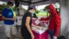 Seorang petugas pemungutan suara dengan kostum super hero membantu para pemilih di sebuah tempat pemungutan suara di Surabaya, 9 Desember 2020. (Foto: AFP)