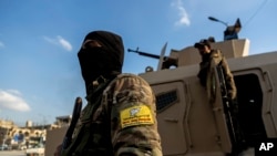 FILE - U.S.-backed Syrian Democratic Forces fighters stand guard at Al Naeem Square, in Raqqa, Syria, Feb. 7, 2022. 