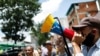 Un hombre sostiene un megáfono con la bandera de Venezuela durante un mitin político opositor antes de las elecciones regionales de noviembre, en Caracas, el 19 de agosto de 2021.