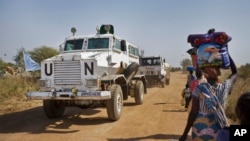 FILE - Displaced people are passed by a United Nations vehicle while walking toward a U.N. camp in Malakal, South Sudan, Dec. 30, 2013. The U.N. is now helping thousands of families in the state of Yei River displaced by months of fighting. 