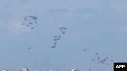 Sejumlah bantuan kemanusiaan untuk wilayah Gaza utara diterjunkan dari udara seperti yang terlihat dari perbatasan antara Israel dan Gaza pada 7 Maret 2024. (Foto: AFP/Jack Guez)