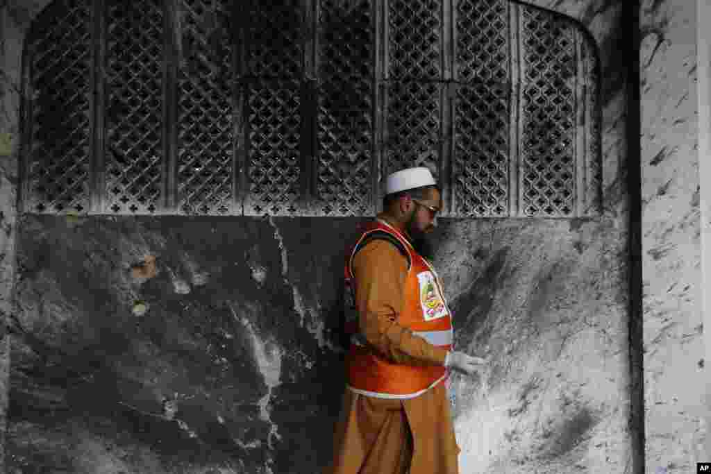 A Pakistani official collects forensic evidence at a Shi'ite mosque attacked by suicide bombers and gunmen in Peshawar, Feb. 13, 2015.
