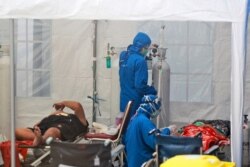 Petugas medis merawat pasien di dalam tenda darurat yang didirikan untuk menampung lonjakan kasus COVID-19, di Rumah Sakit Umum Dr. Sardjito Yogyakarta, 4 Juli 2021. (Foto: AP)