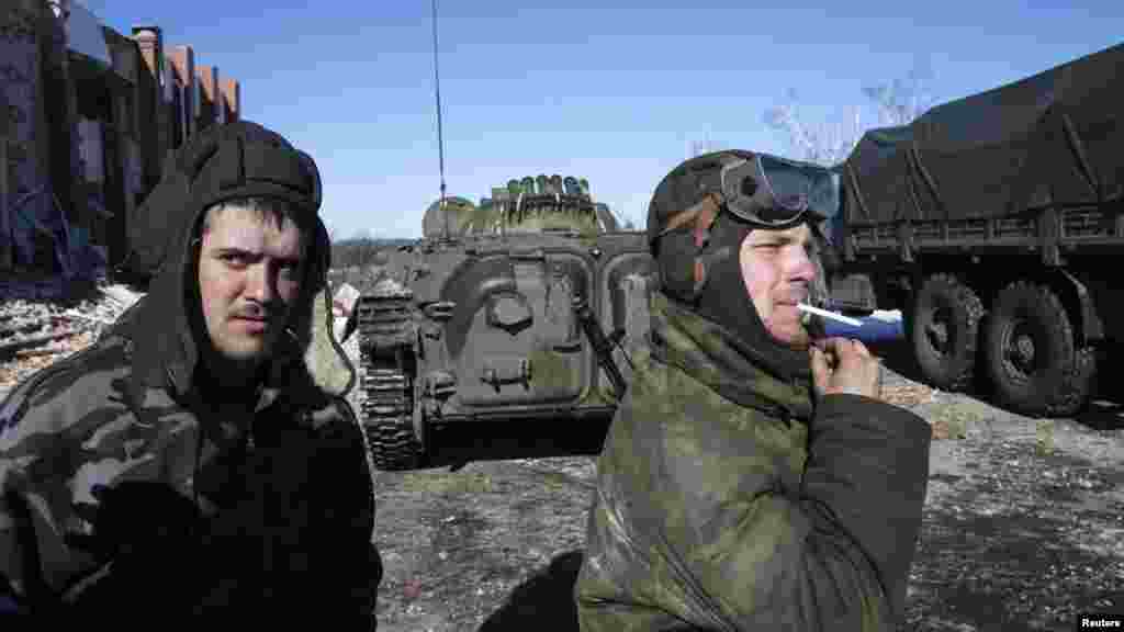 Fighters from the separatist-controlled Donetsk region smoke near an armored personnel carrier in the village of Nikishine, southeast of Debaltseve, Feb. 17, 2015.