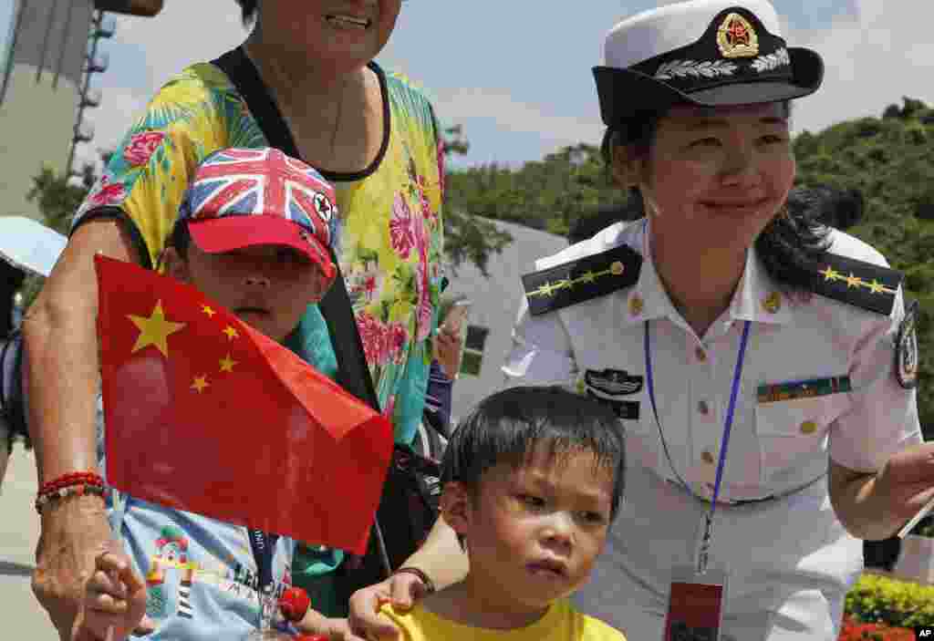 Visitors pose with Chinese People's Liberation Army (PLA) personnel during opening day of Stonecutter Island Navy Base to mark the 18th anniversary of the Hong Kong handover to China, in Hong Kong, July 1, 2015.