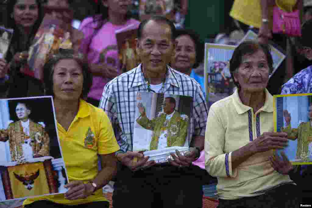 Well-wishers hold pictures of Thailand's King Bhumibol Adulyadej, Dec. 4, 2013, as they camp outside the palace where he is staying in Hua Hin, Prachuap Khiri Khan province, Thailand, a day before his birthday.