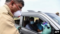 Seorang petugas polisi Uttar Pradesh memberikan bunga kepada seorang pengendara dan meminta mereka untuk tetap tinggal di dalam rumah di pos pemeriksaan selama karantina nasional yang diberlakukan pemerintah sebagai tindakan pencegahan terhadap virus corona COVID-19 di New Delhi